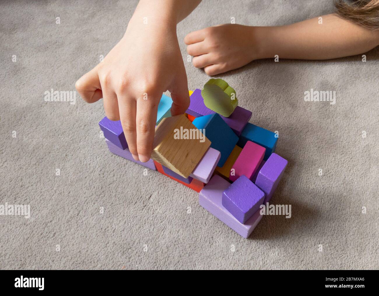 Un enfant joue avec un coeur coloré avec des blocs de construction en bois colorés. Concept de journée mondiale de sensibilisation à l'autisme. Banque D'Images