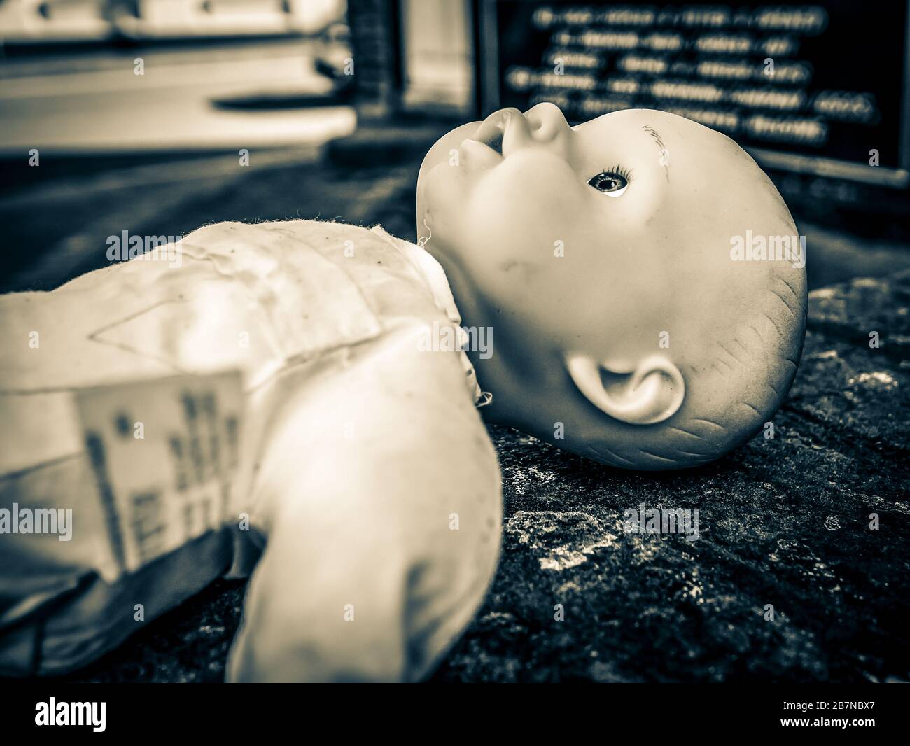Poupée de bébé abandonnée laissée sur un mur dans Split Tone Banque D'Images