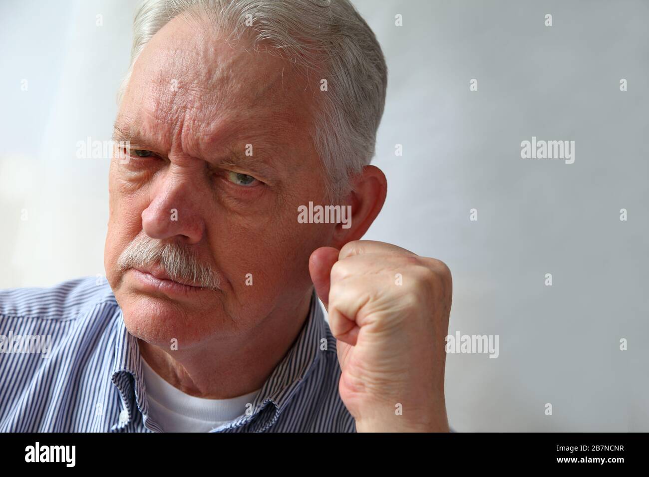 L'homme senior a l'air hostile et les gestes avec l'espace de copie Banque D'Images