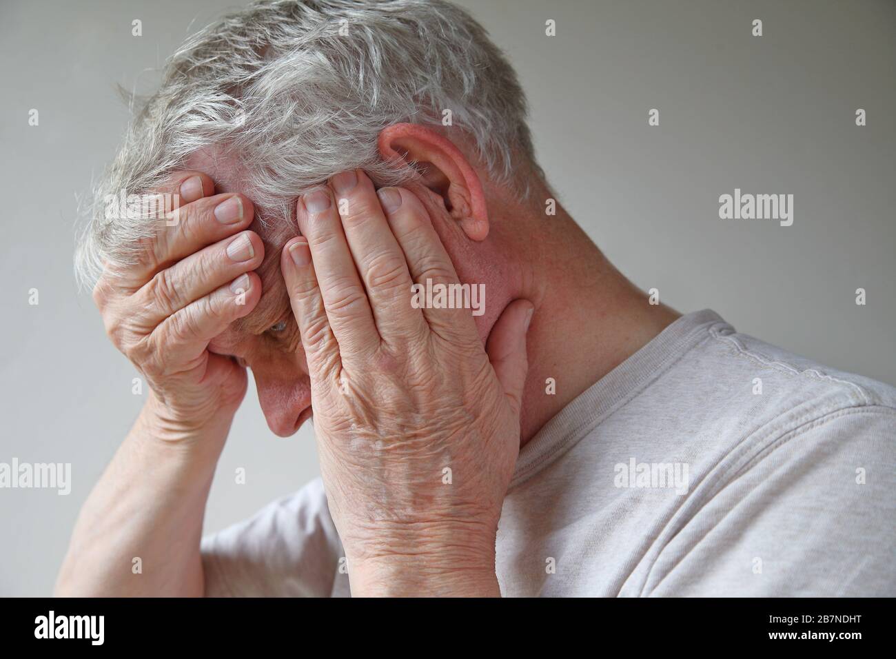 Homme senior avec ses mains couvrant presque son visage Banque D'Images