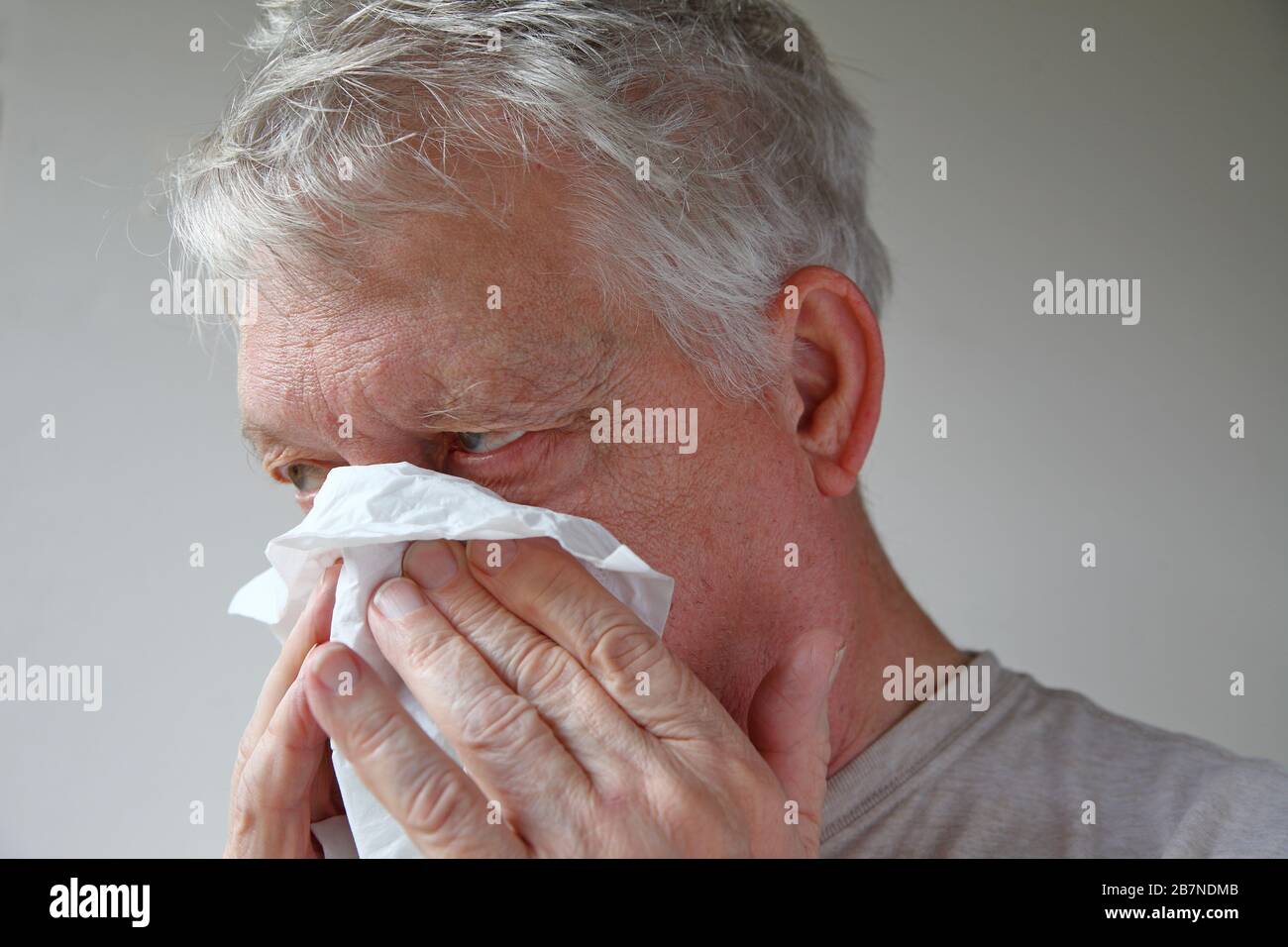 En utilisant un tissu, un homme plus âgé souffle son nez avec de la place pour le texte Banque D'Images