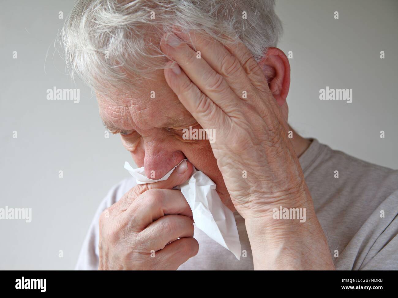 Homme senior avec un tissu à son nez et une main sur sa tête de braconnage Banque D'Images