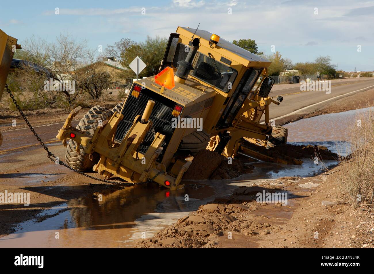 Un niveleur qui s'est coincé dans la boue le long d'une route d'Arizona après les pluies de mousson. Banque D'Images