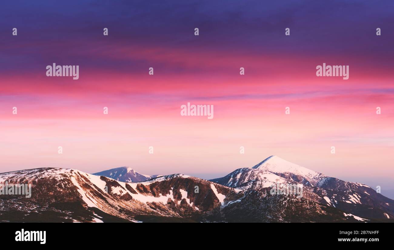 Lumière de lever de soleil violette qui brille sur les sommets enneigés des montagnes en arrière-plan. Photographie de paysage Banque D'Images