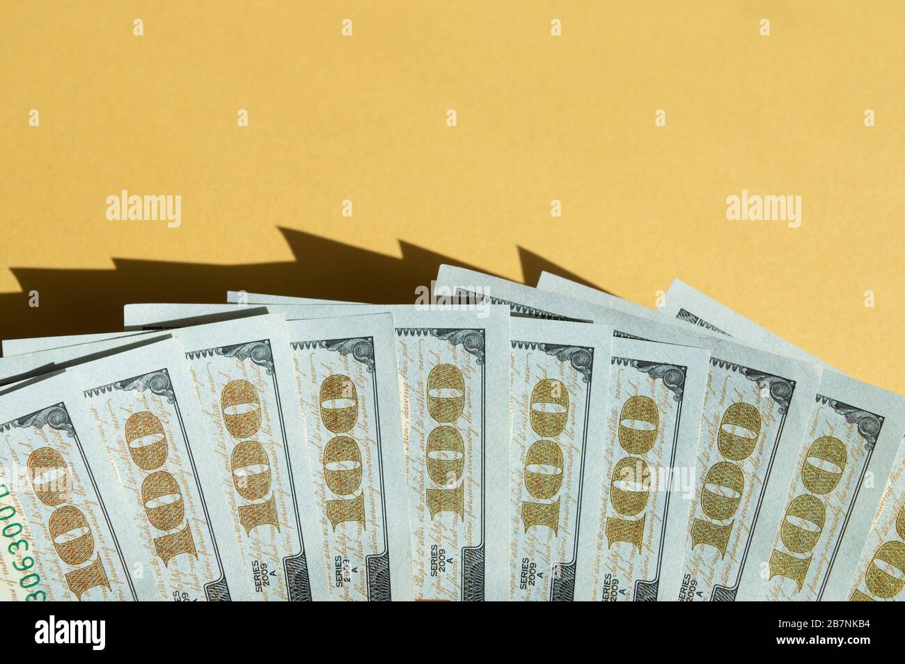 Dix factures de 100 dollars sur fond jaune et bleu. Photo conceptuelle, conception minimaliste de la monnaie des États-Unis Banque D'Images