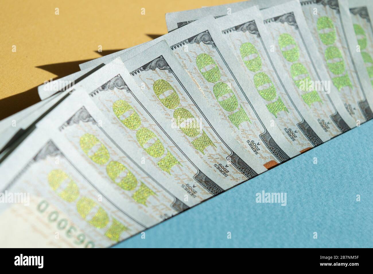 Neuf factures de 100 dollars sur fond jaune et bleu. Photo conceptuelle, conception minimaliste de la monnaie Banque D'Images