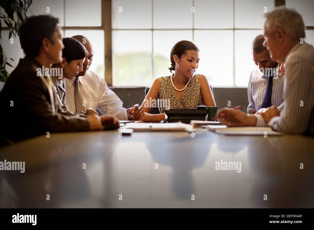 Femme d'affaires de taille moyenne assise dans une salle de réunion avec collègues. Banque D'Images