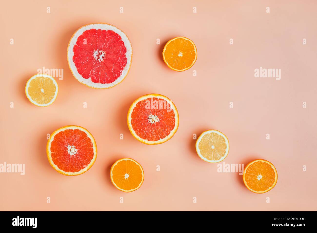 Composition de la couche plate avec les moitiés de différents agrumes sur fond rose. Banque D'Images