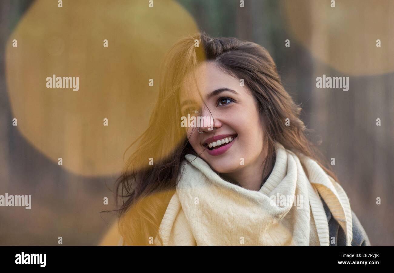 Charmante jeune femme brunette gaie dans un foulard blanc en maille regardant à l'extérieur en automne Banque D'Images