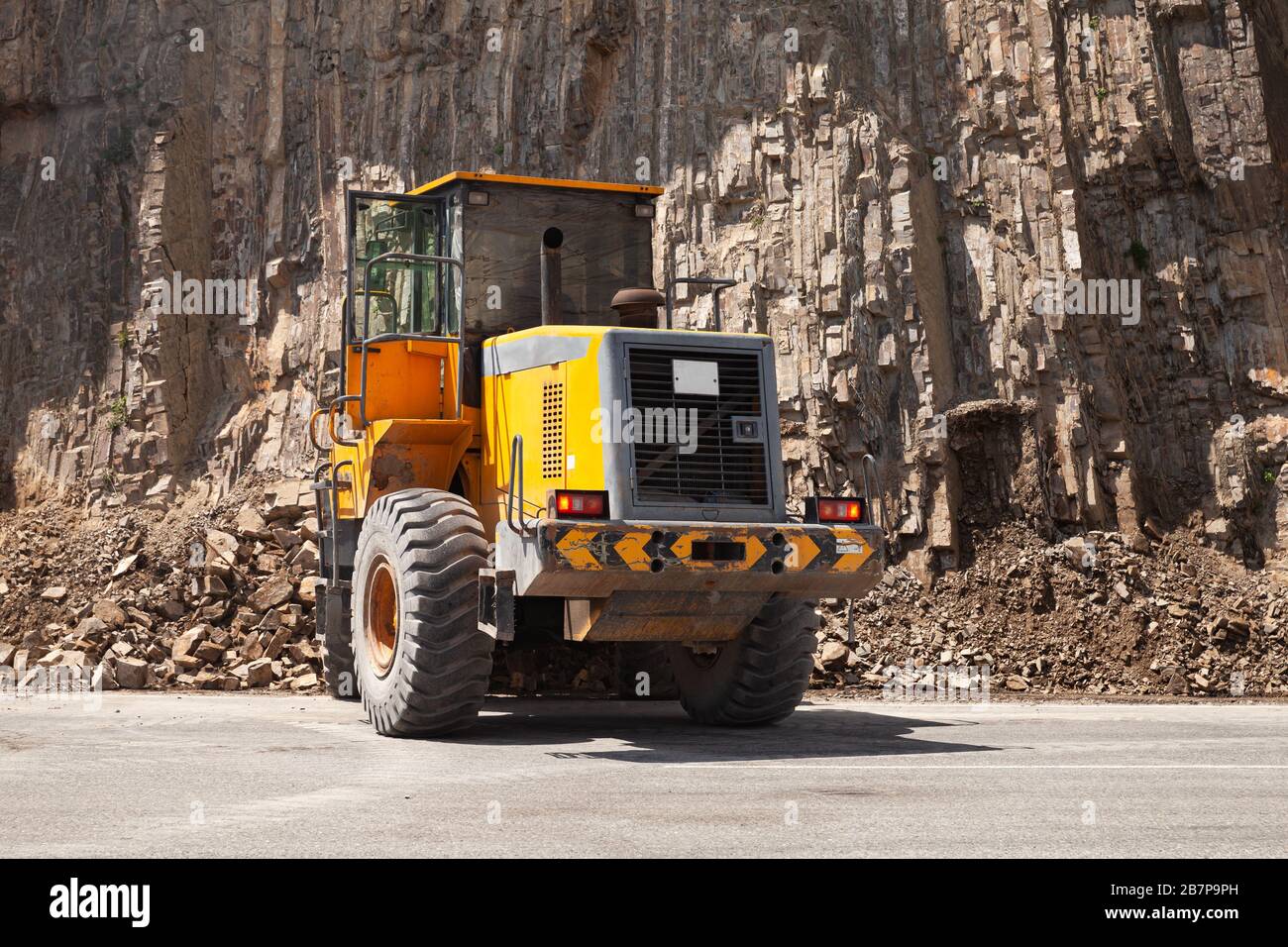 Le tracteur jaune se dégage d'une route de montagne après un glissement de terrain. Ville d'Ananuri, Géorgie Banque D'Images