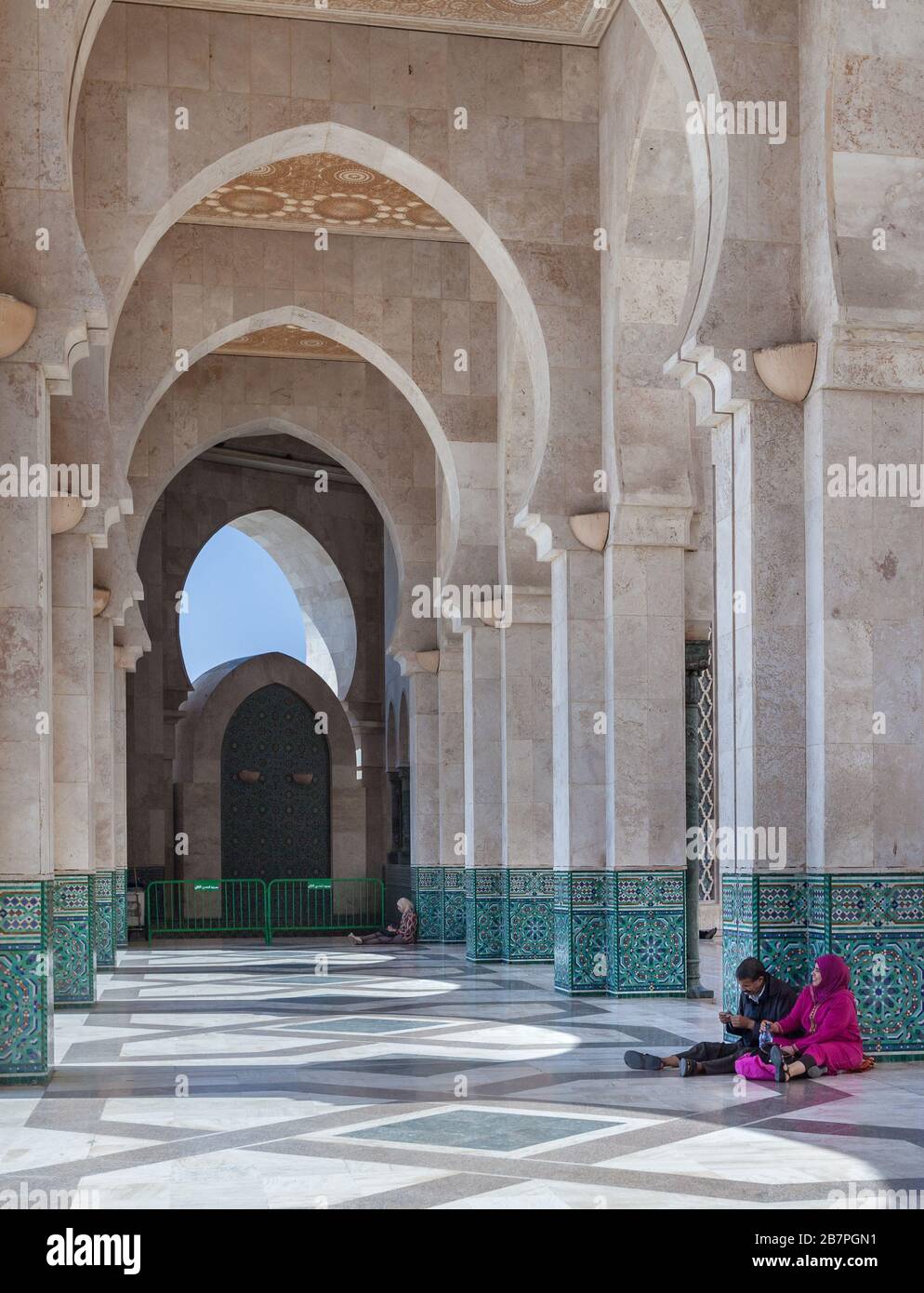Casablanca, Maroc : des gens en vêtements traditionnels assis à l'étage sous les arches de la Mosquée Hassan Banque D'Images