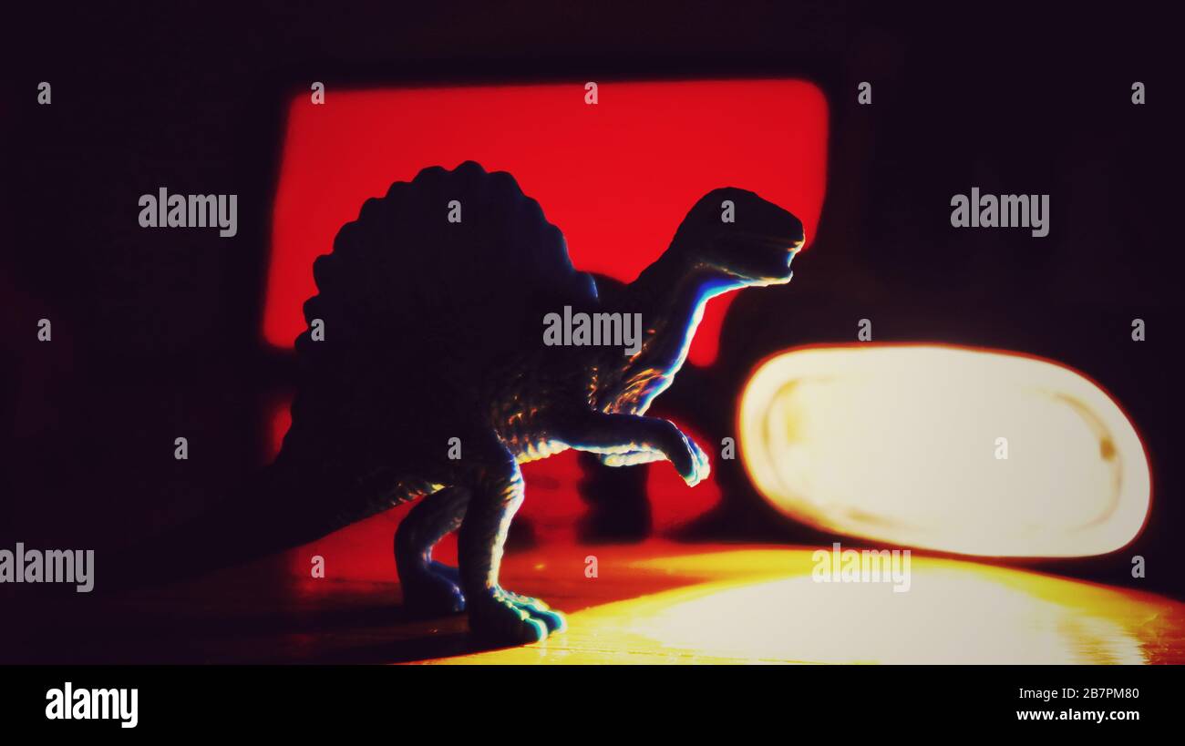 Dinosaure bleu avec lumière rouge dramatique nous regardant Banque D'Images