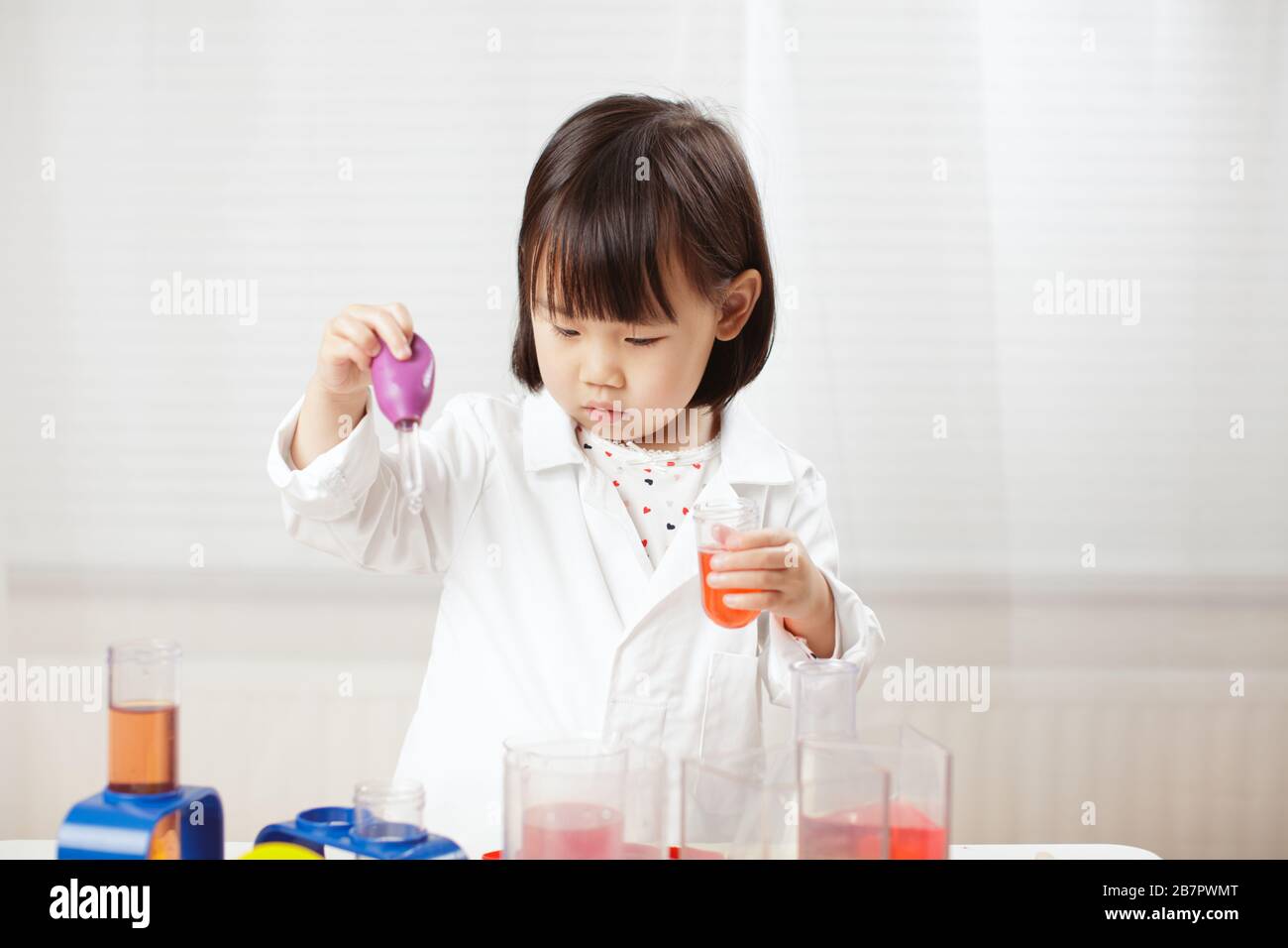 Bébé fille prétendre jouer un rôle scientifique à domicile contre le fond blanc Banque D'Images