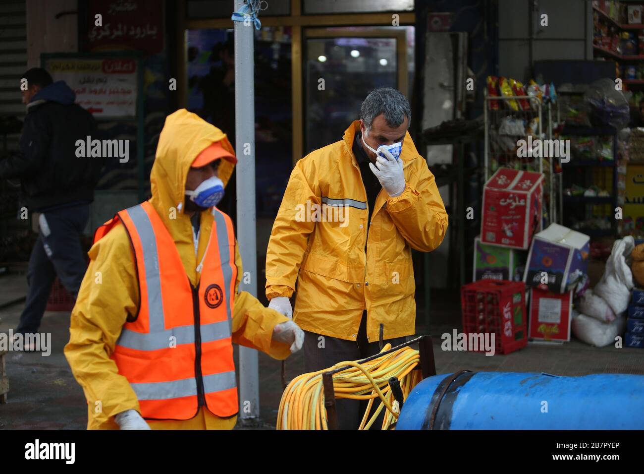 Les travailleurs de la municipalité portant des vêtements de protection désinfectent une rue de la bande de Gaza le 14 mars 2020 afin d'empêcher la propagation du Coronavirus. Banque D'Images