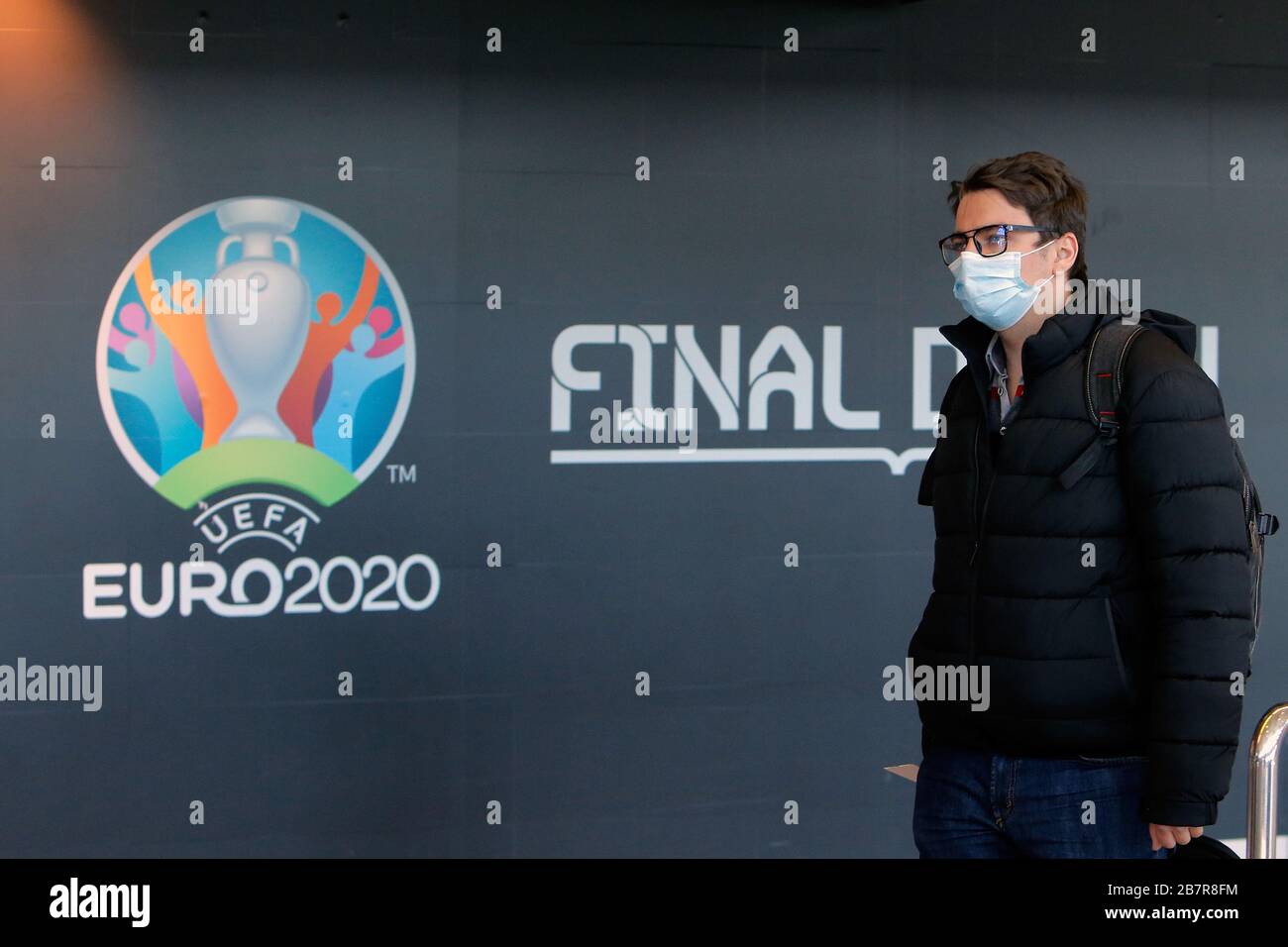 (200318) -- BUCAREST, le 18 mars 2020 (Xinhua) -- un homme portant un masque de visage passe par un logo du championnat européen DE football EURO 2020 exposé sur un mur à l'aéroport international Henri Coanda de Bucarest, Roumanie, le 17 mars 2020. L'organe directeur européen du football de l'UEFA a décidé de reporter le championnat d'Europe de cet été à 2021 en raison de l'épidémie de coronavirus. Le président roumain Klaus Iohannis a annoncé que le pays entrera dans un état d'urgence à partir du 16 mars, dans un effort pour s'assurer que le gouvernement utilise toutes les ressources pour lutter contre l'épidémie de COVID-19. (Photo de Cris Banque D'Images