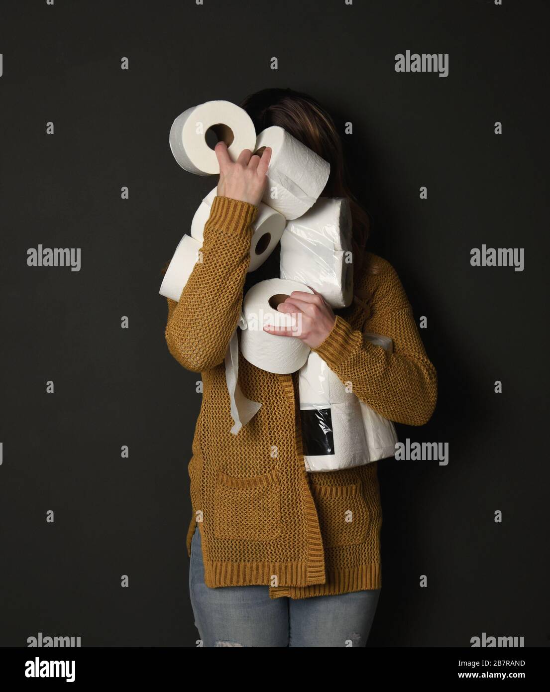 Une femme tient une pile de fournitures de papier toilette pour un concept de demande des consommateurs concernant la pandémie du virus corona. Banque D'Images
