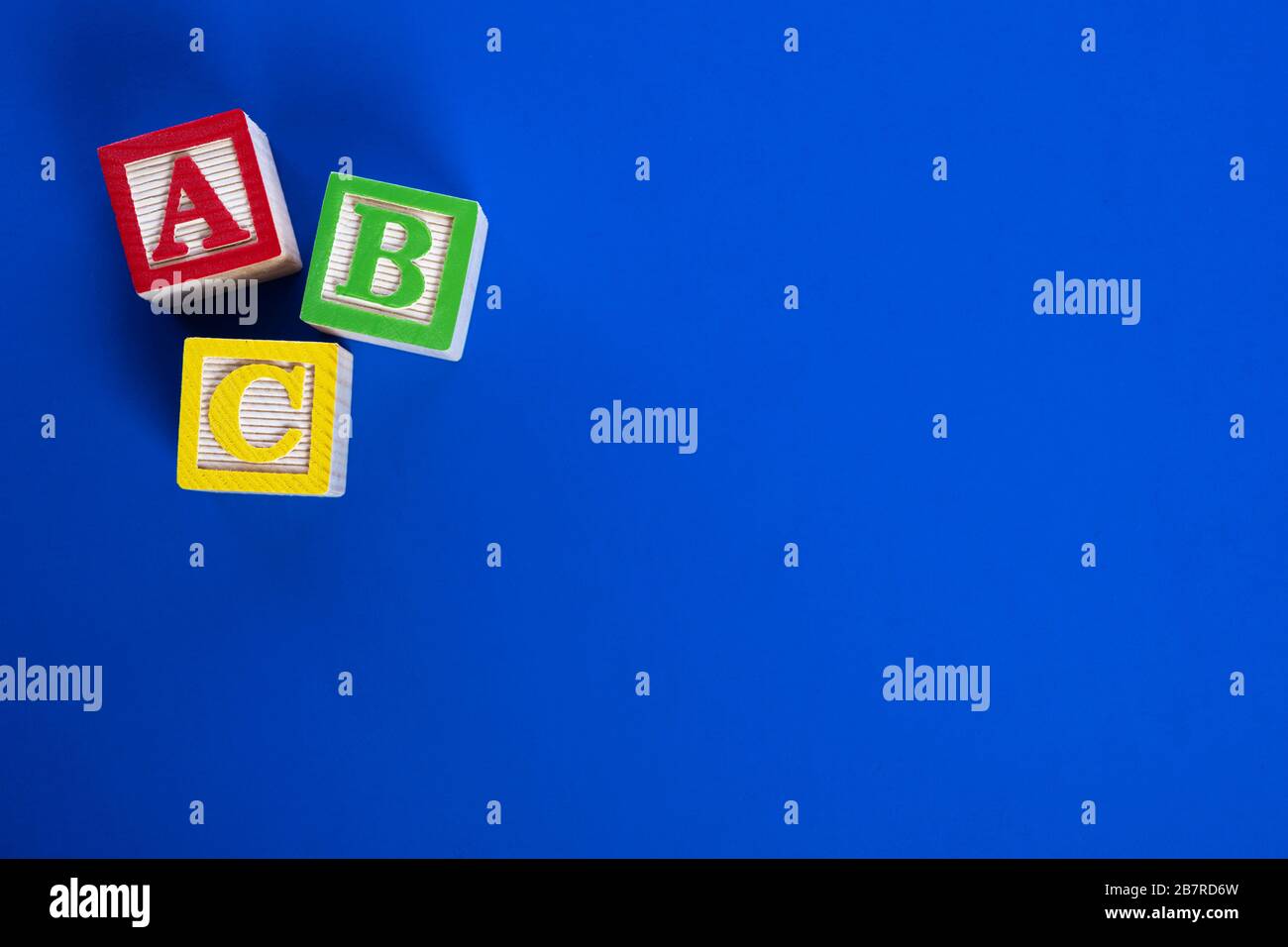 Un ensemble coloré de blocs ABC en bois sur fond bleu vif Banque D'Images