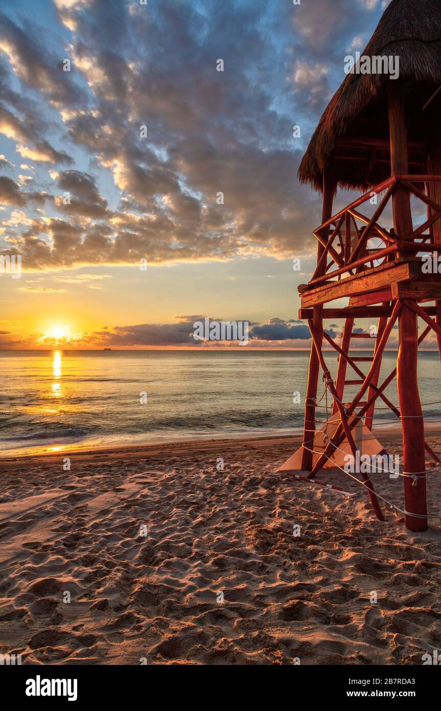 Lever du soleil sur les plages tropicales de la Riviera Maya près de Cancun, au Mexique, avec tour de sauveteur surplombant la mer des Caraïbes. Orientation verticale. Banque D'Images