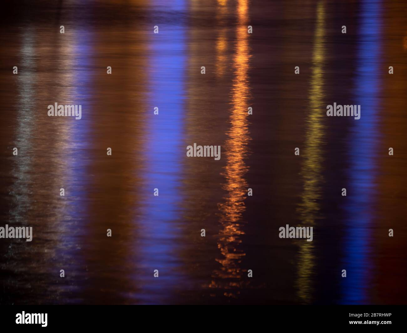 Réflexion lumineuse colorée sur la surface de l'eau. Vagues d'eau de mer la nuit. Texture de fond. Banque D'Images