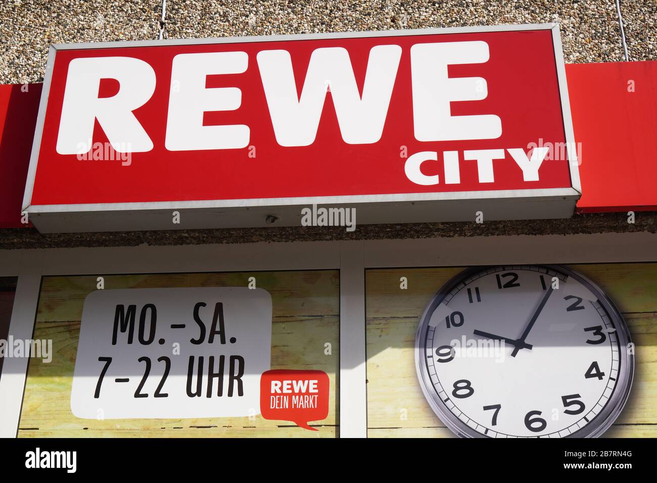 Hanovre, Allemagne - 17 mars 2020: Panneau du logo Rewe City et horaires d'ouverture ou heures d'ouverture à la succursale locale de la chaîne de supermarchés allemande Banque D'Images