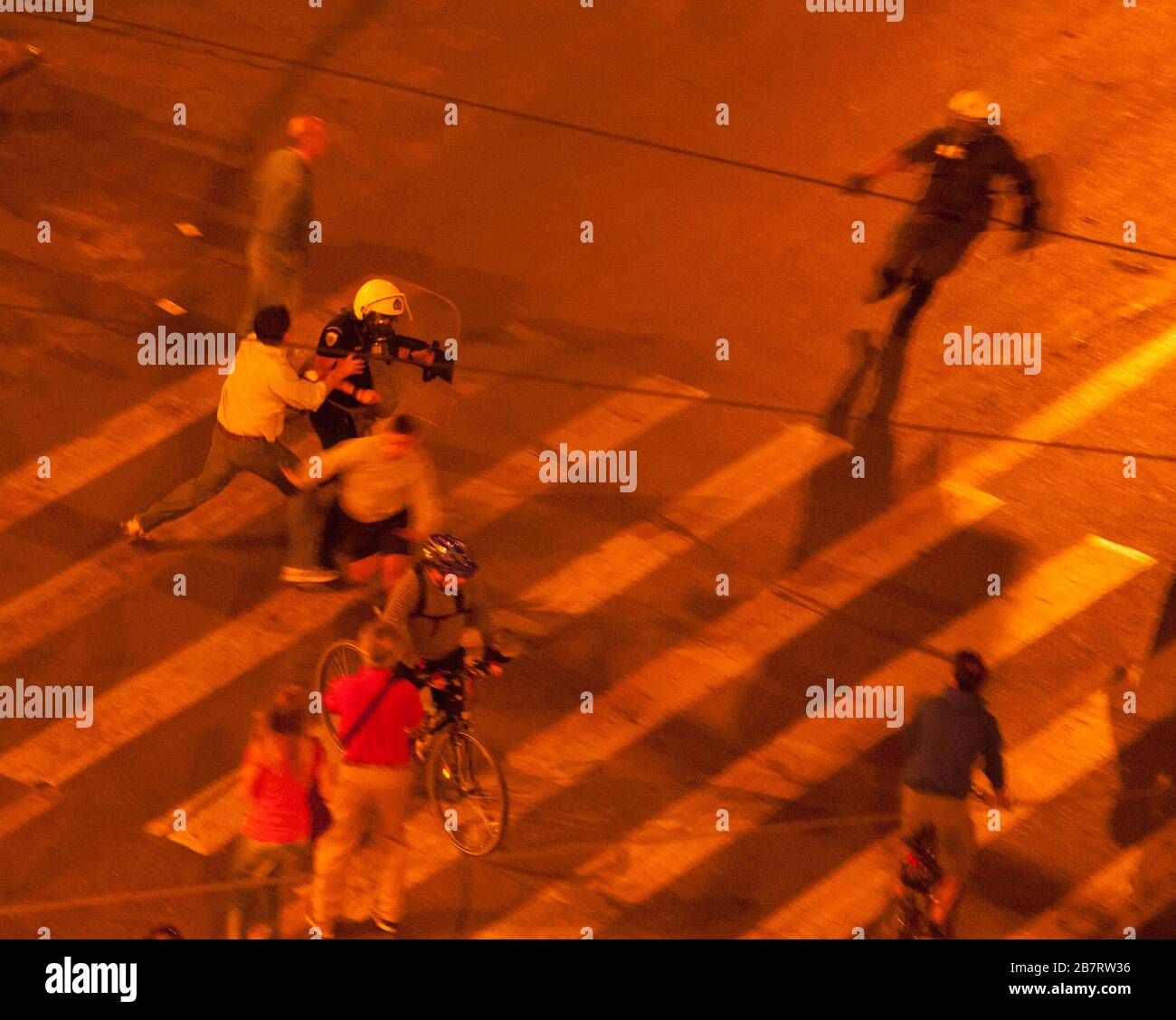 Des manifestants attrapant un policier dans la rue à Athènes, Grèce, en public manifestations sur le passage en piétons avec d'autres piétons à pied et à vélo horizontale Banque D'Images