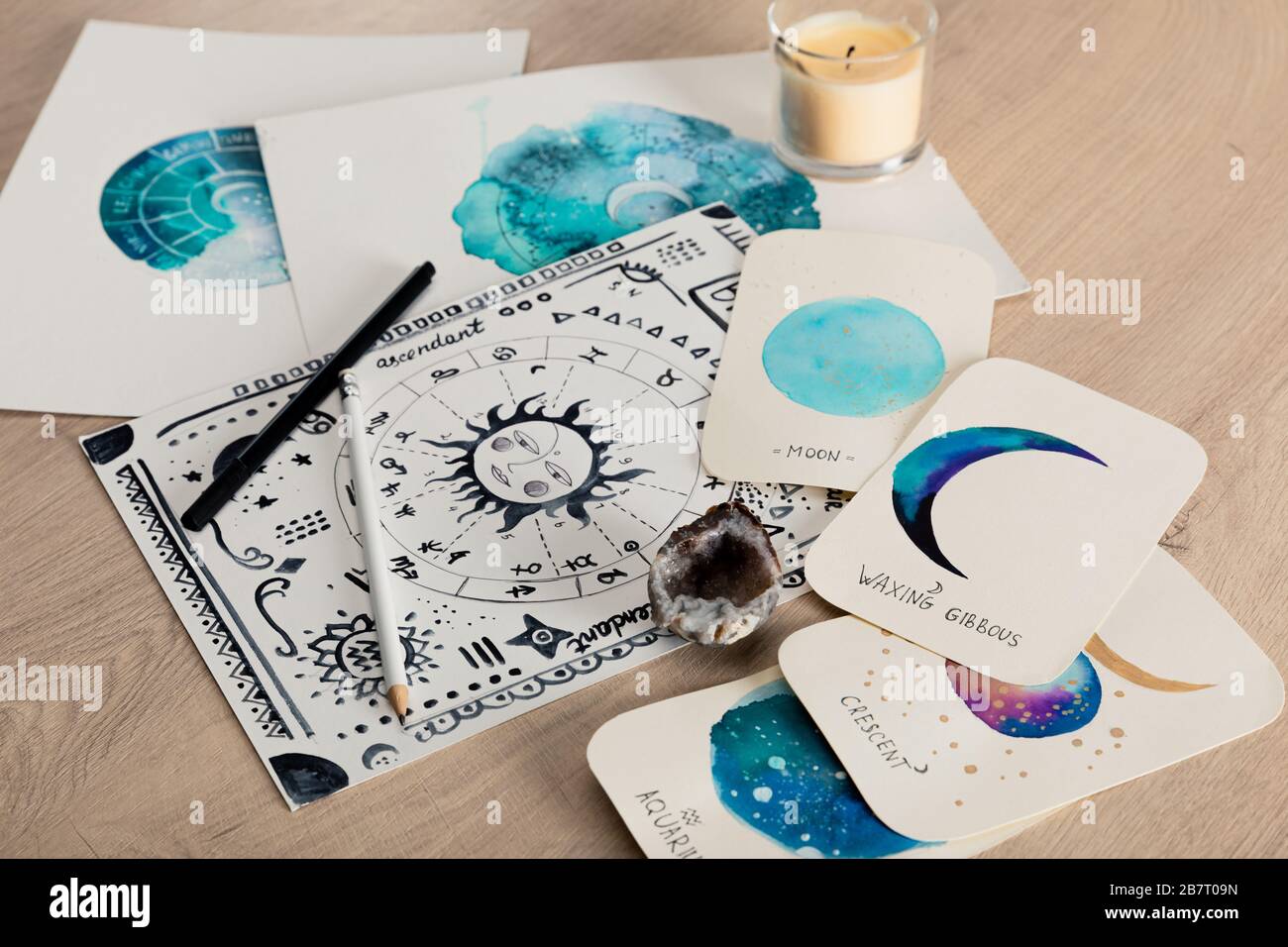 Foyer sélectif de la carte de naissance et des cartes avec des dessins aquarelle des phases de lune et bougie sur table Banque D'Images