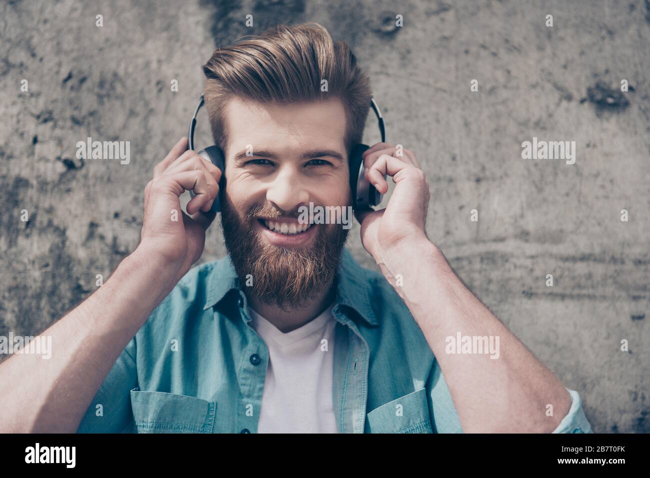 Joli gars rouge barbu avec sourire et coiffure à la mode parfaite écoute de la musique à l'extérieur avec un grand casque Banque D'Images