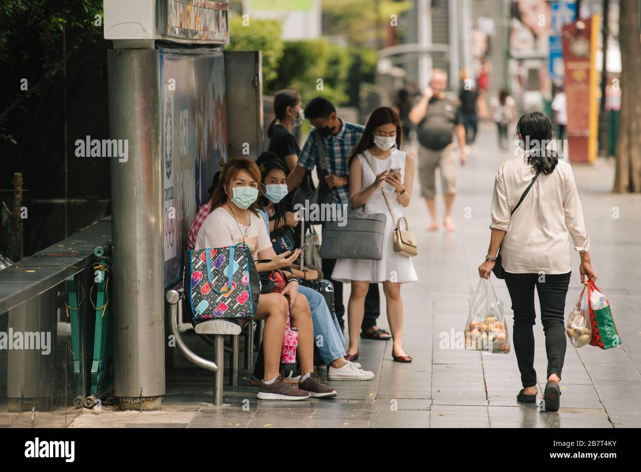 Les personnes portant des masques de protection pour arrêter la propagation du virus corona attendent un arrêt de bus à Bangkok, Thaïlande Banque D'Images