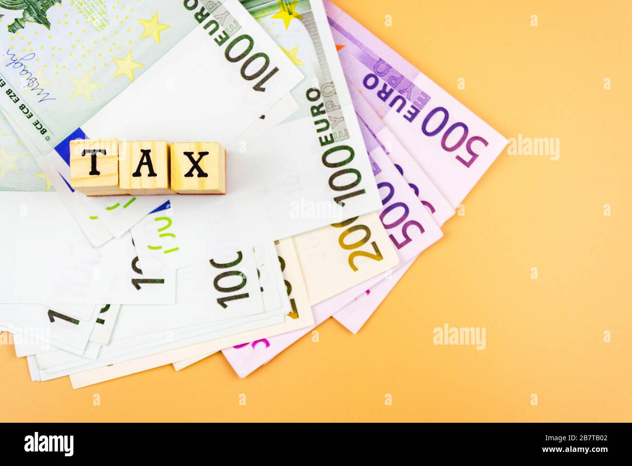 Le mot taxe et la monnaie de l'Union européenne de différentes dénominations sur un fond orange 4 Banque D'Images
