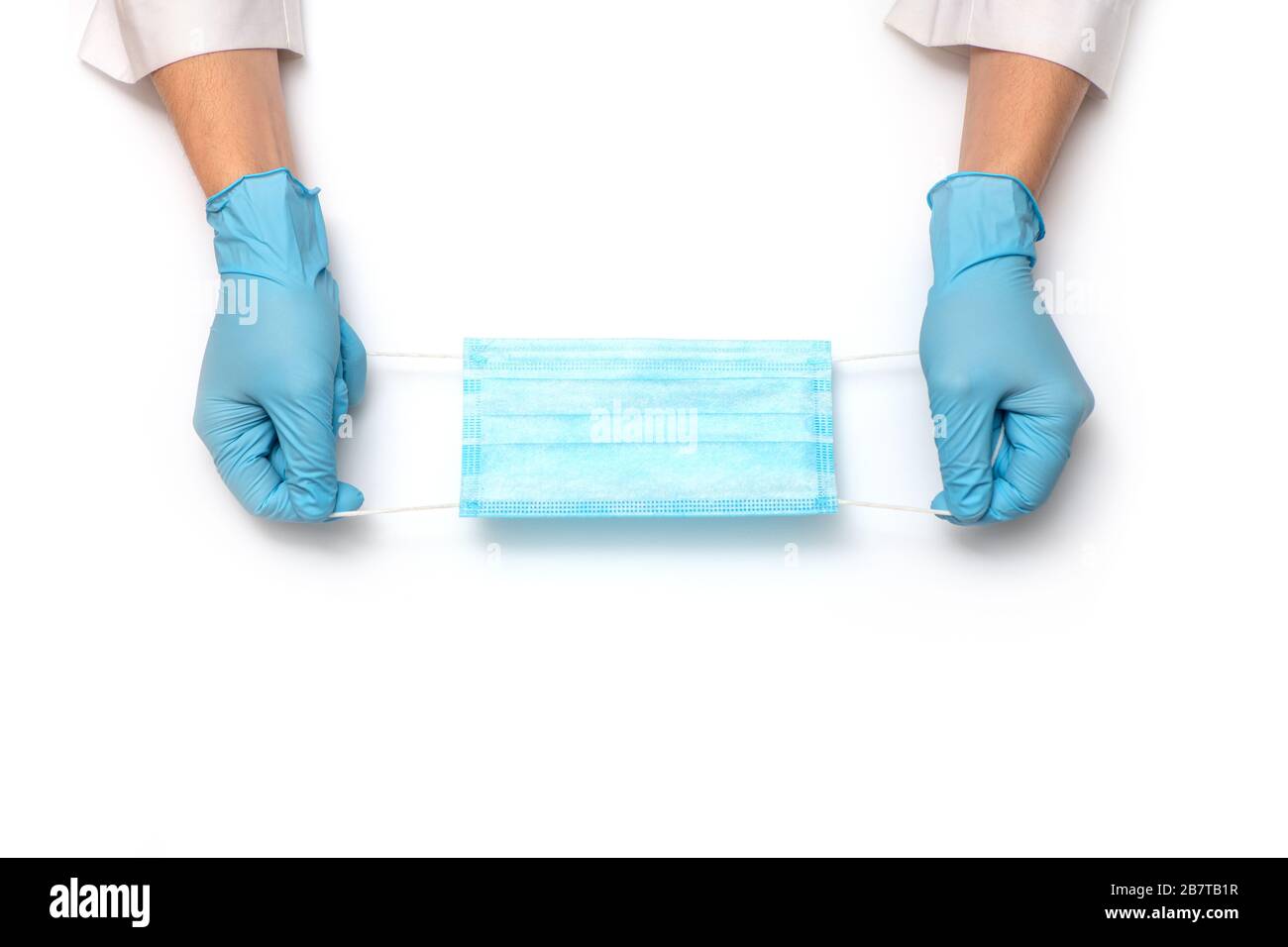 Mains dans des gants médicaux portant un masque de protection médicale sur fond blanc. Vue de dessus. Banque D'Images