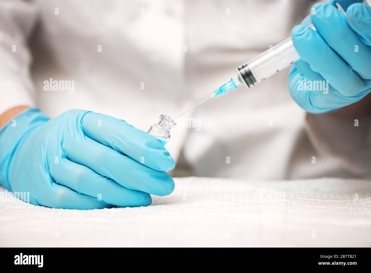 Le médecin ou l'infirmière mains dans des gants bleus contenant une seringue et une injection de vaccin. Concept de médecine. Banque D'Images