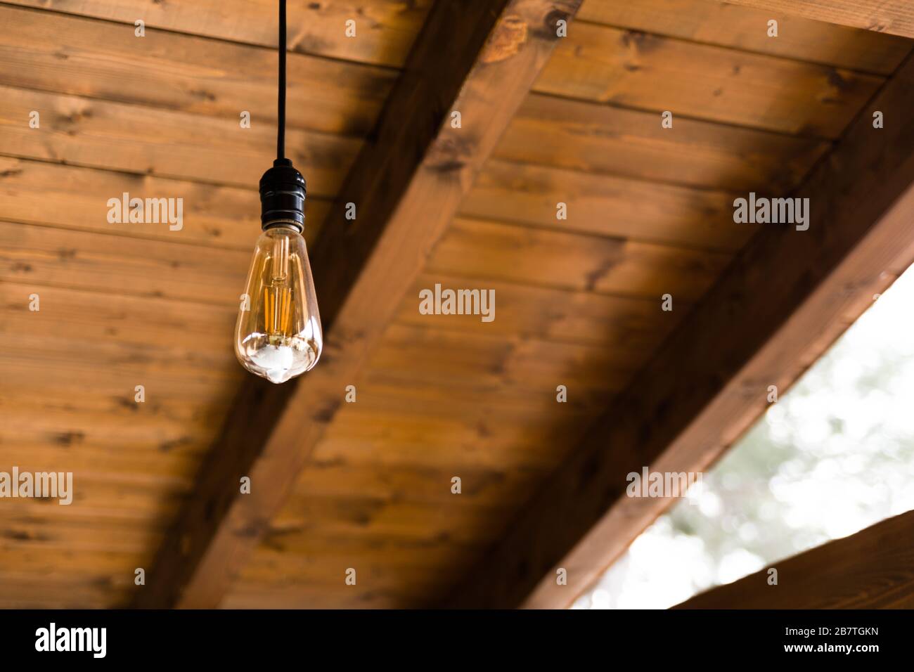 Ampoule rétro sur un plafond en bois chaud Banque D'Images