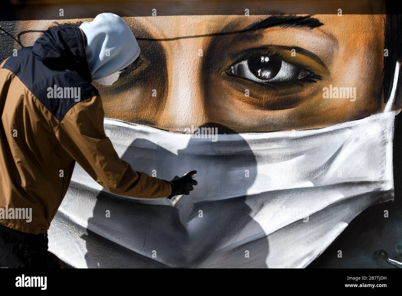 Athènes, Grèce - 17 mars 2020: Un jeune homme fait un graffiti inspiré par les mesures contre le coronavirus (COVID-19) sur la terrasse d'un bloc de Banque D'Images