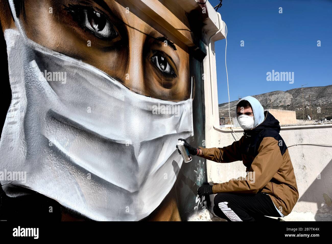 Athènes, Grèce - 17 mars 2020: Un jeune homme fait un graffiti inspiré par les mesures contre le coronavirus (COVID-19) sur la terrasse d'un bloc de Banque D'Images