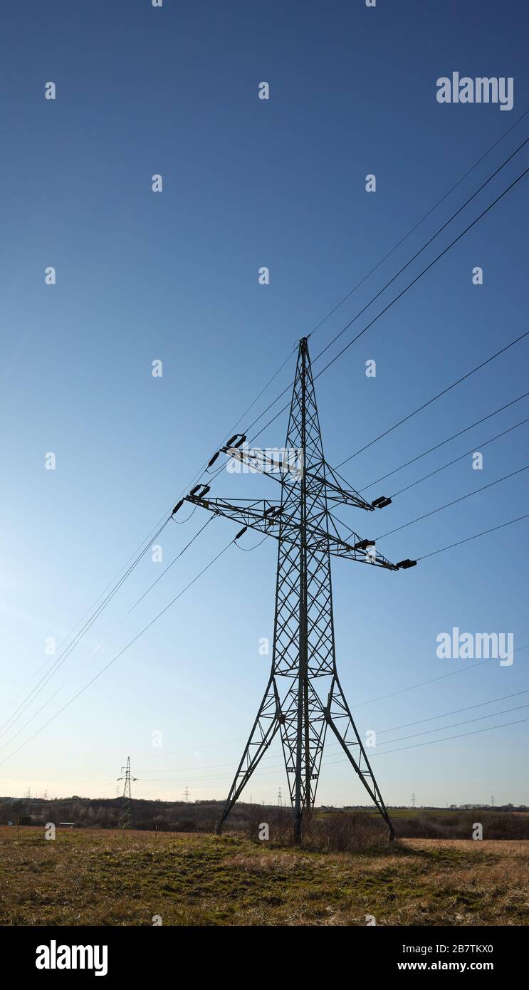 Tour de transmission haute tension sur un champ contre le soleil. Banque D'Images