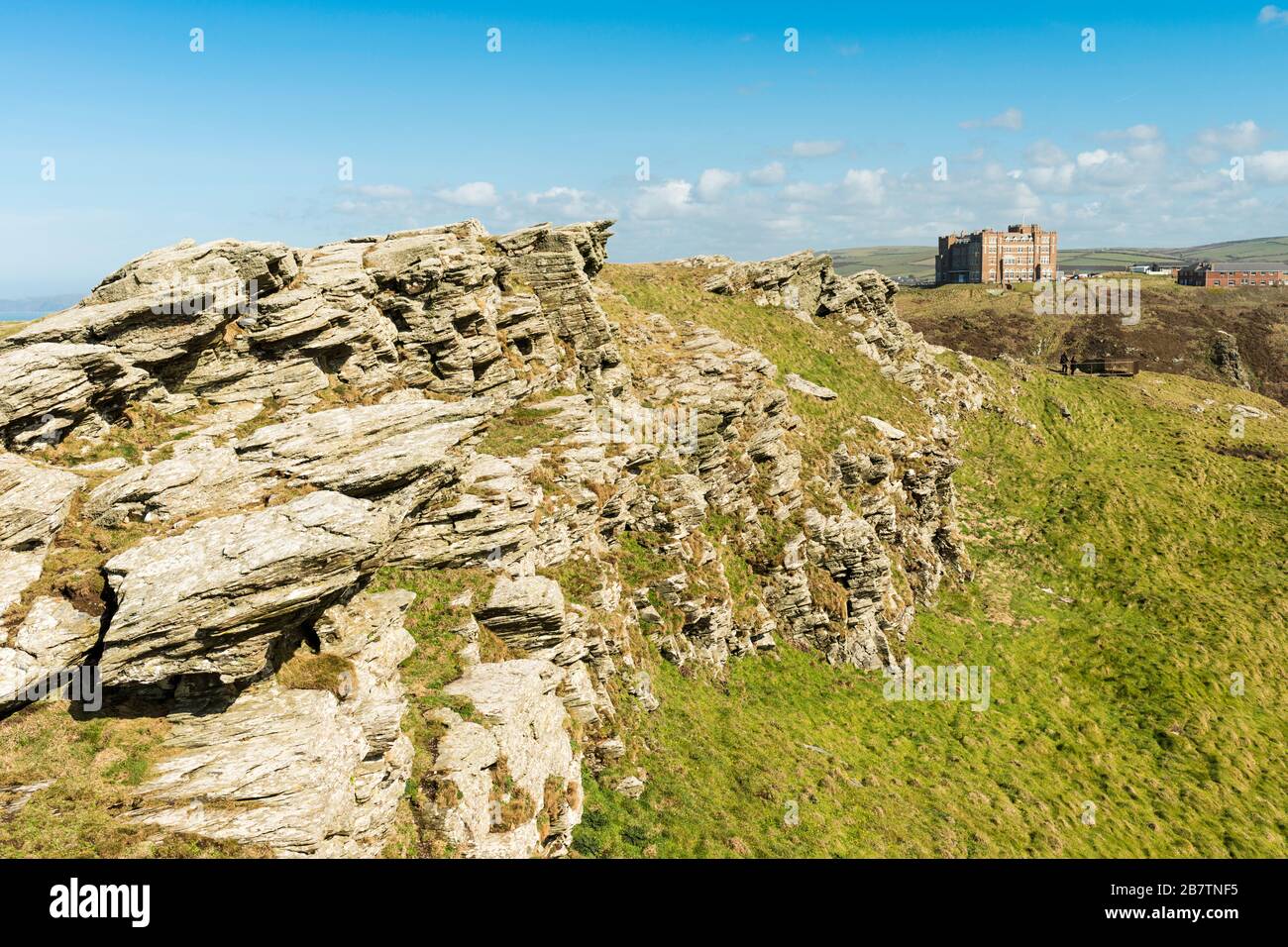 Paysage rocheux sur l'île du château de Tintagel, avec le 'Camelot Castle Hotel' (1899) sur le promontoire éloigné. Tintagel, Cornwall, Royaume-Uni. Banque D'Images