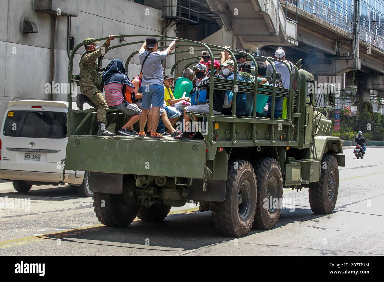 Makati City. 18 mars 2020. Les gens sont vus sur un camion militaire offrant des tours gratuits aux passagers bloqués après que le gouvernement philippin a ordonné la suspension des installations de transport en commun de masse conformément à la « quarantaine communautaire améliorée » à Makati City, aux Philippines, le 18 mars 2020. Crédit: Rouelle Umali/Xinhua/Alay Live News Banque D'Images