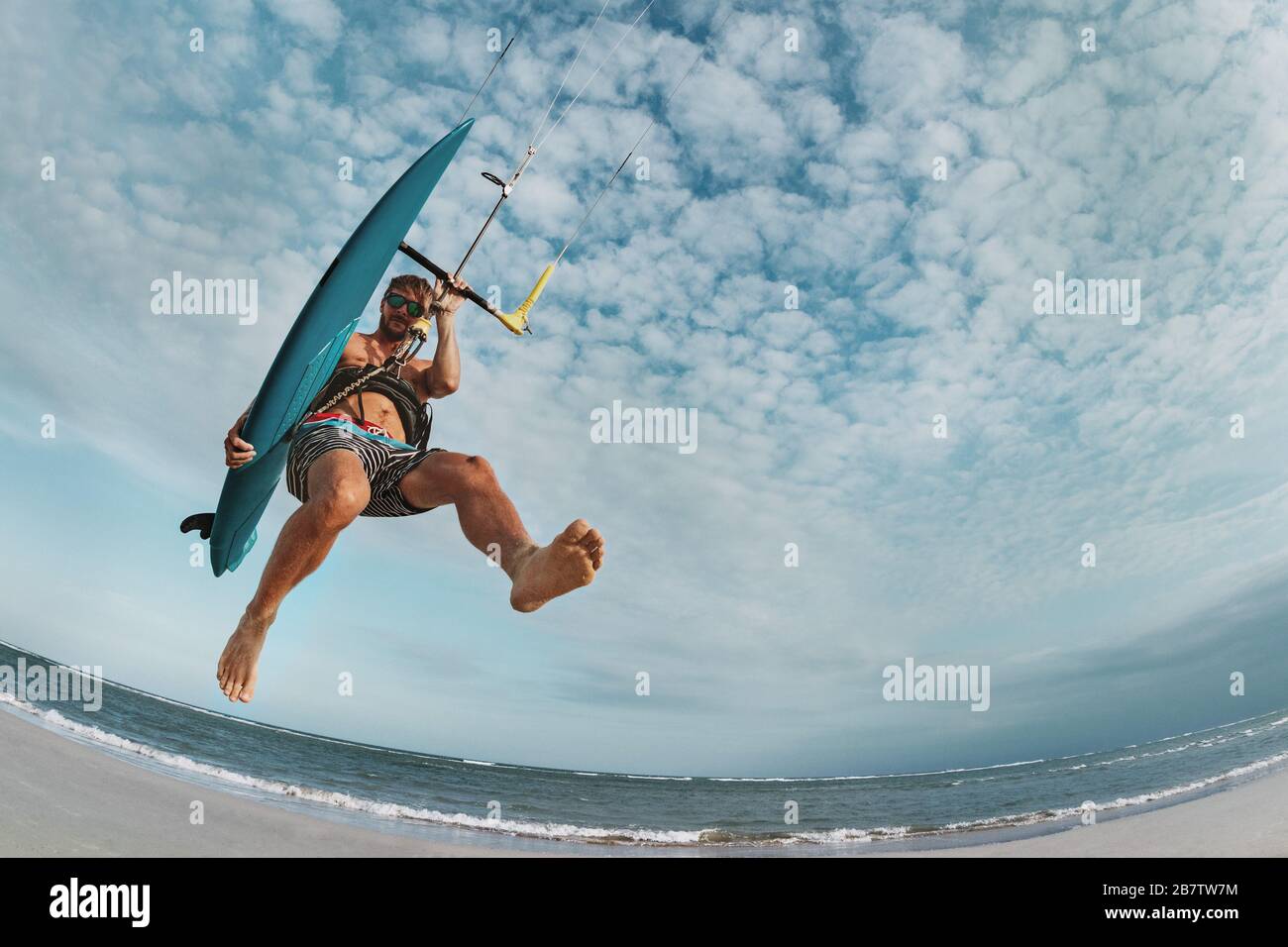 L'homme kite surfeur saute avec wakeboard à la plage de la mer Banque D'Images