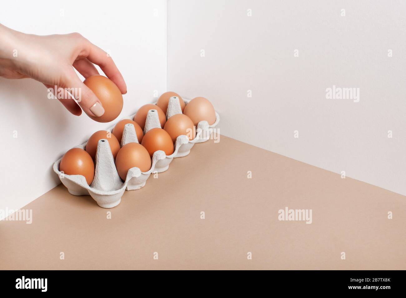 La main femelle prend un œuf de la boîte. Concept de nourriture minimaliste, régime de keto. Banque D'Images