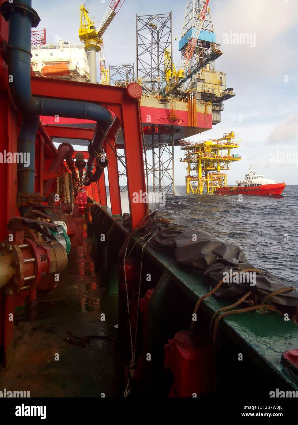 le navire de soutien offshore se trouve à 500 mètres de la nouvelle plate-forme pétrolière pour recevoir du fret par l'opérateur de grue Banque D'Images