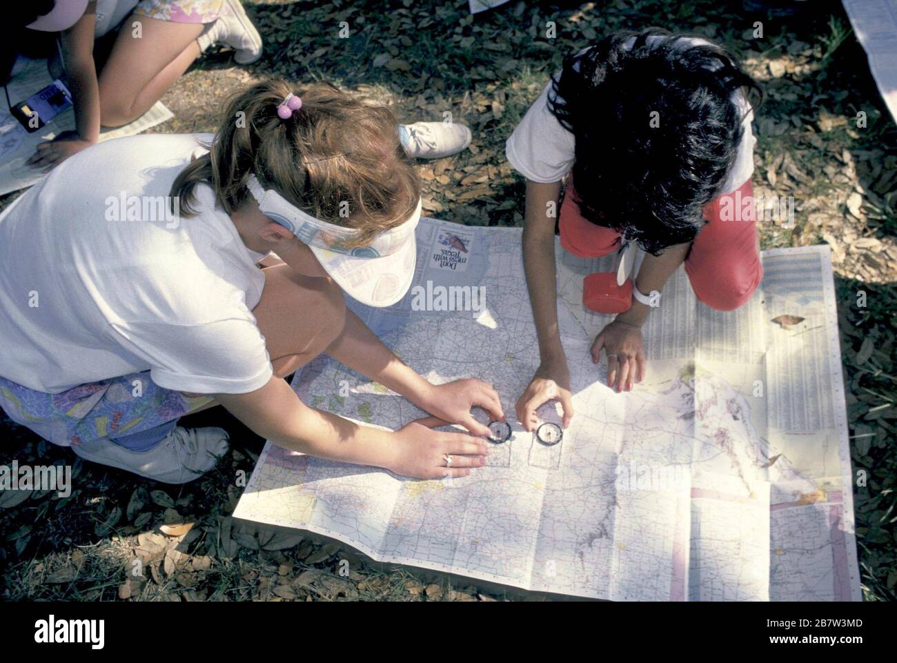 Bandera, Texas États-Unis, vers 1991: Les filles de quatrième année utilisent la boussole et la carte pour estimer leur emplacement au cours d'une excursion de nuit de camping scolaire. ©Bob Daemmrich Banque D'Images