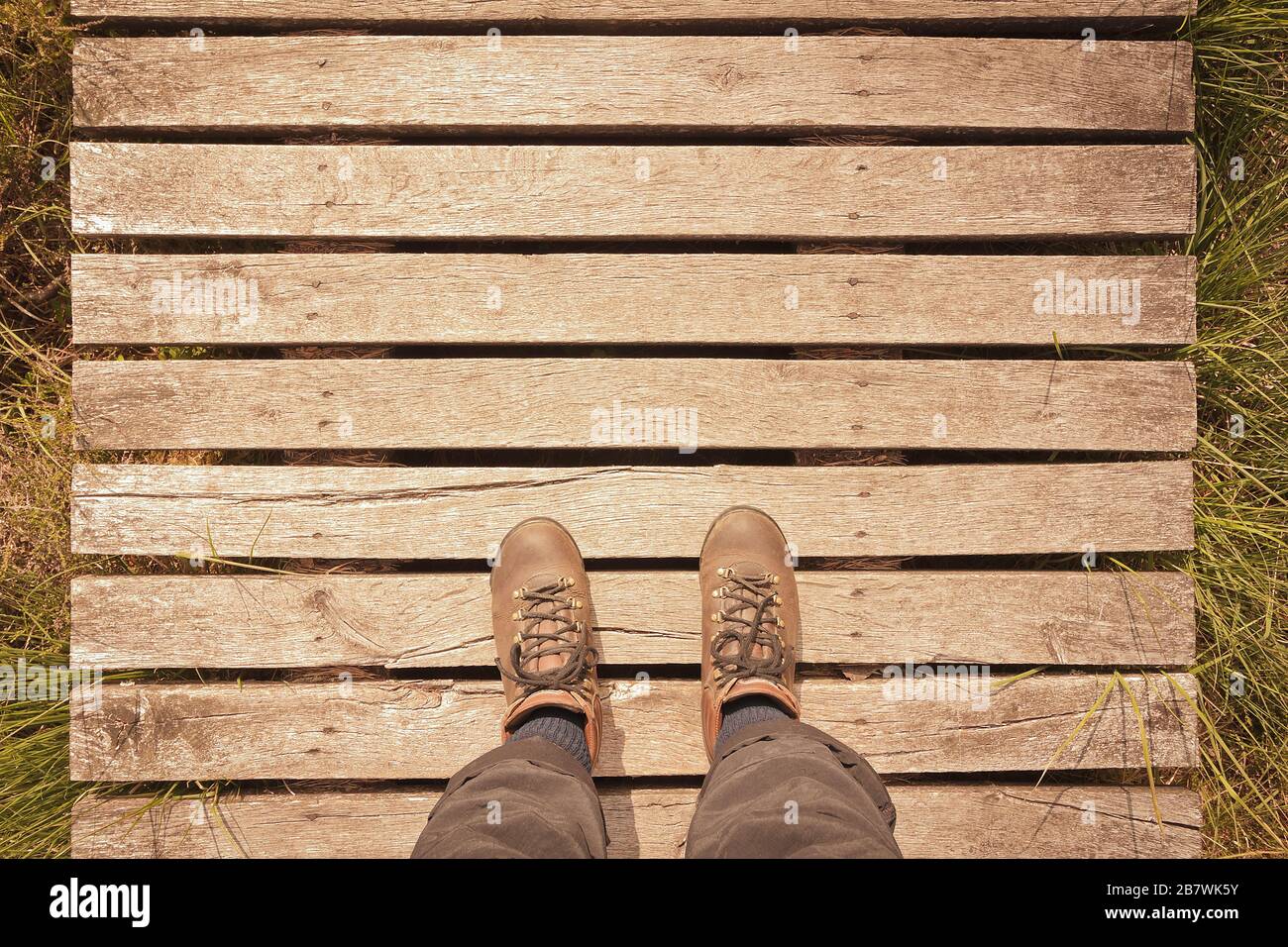 Bottes de randonnée sur une promenade en bois avec espace de copie, concept pov, effet filtre vintage. Banque D'Images