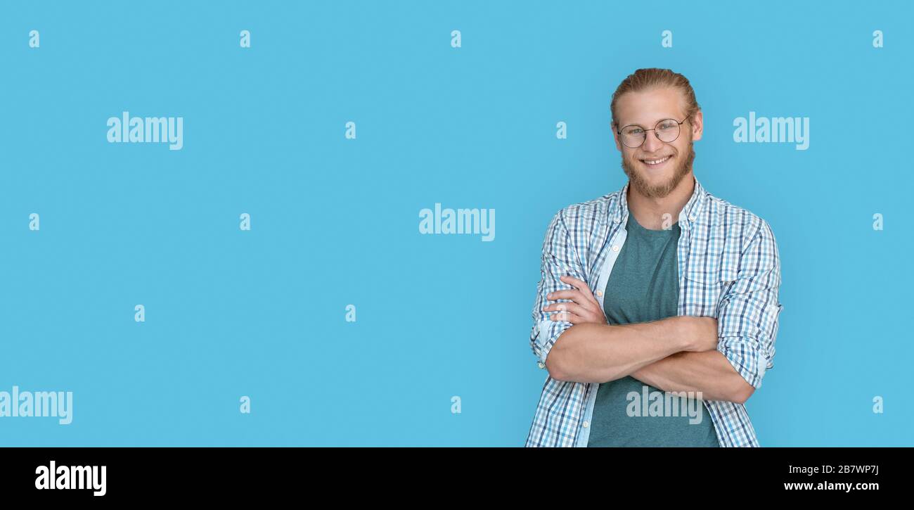 Les bras de l'homme souriants et confiants ont traversé l'image de la caméra isolée sur fond bleu. Banque D'Images