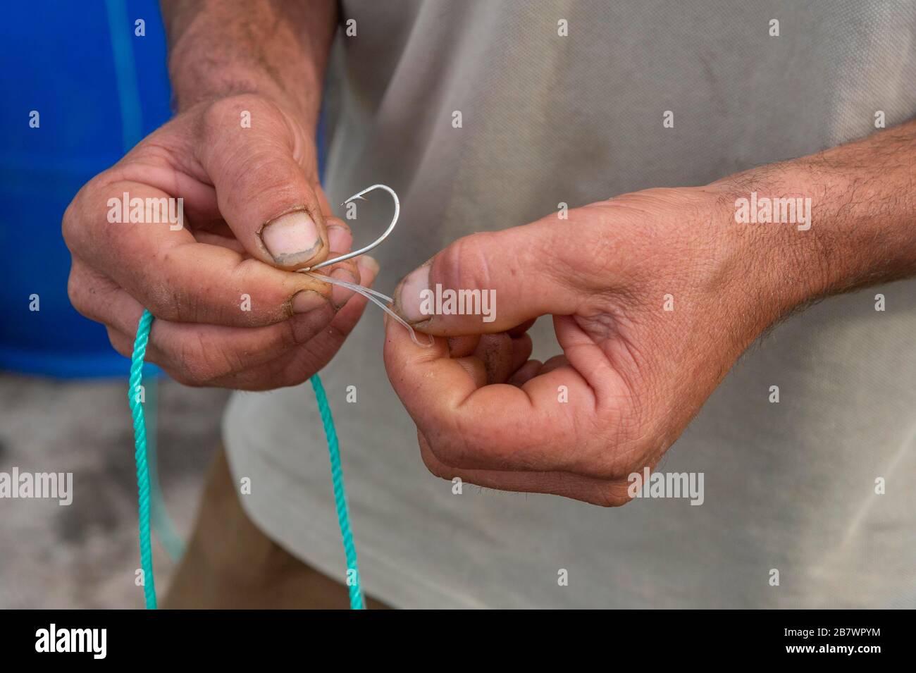 Pêcheur noeuds un crochet de pêche sur la ligne, San Miguel, Açores, Portugal Banque D'Images