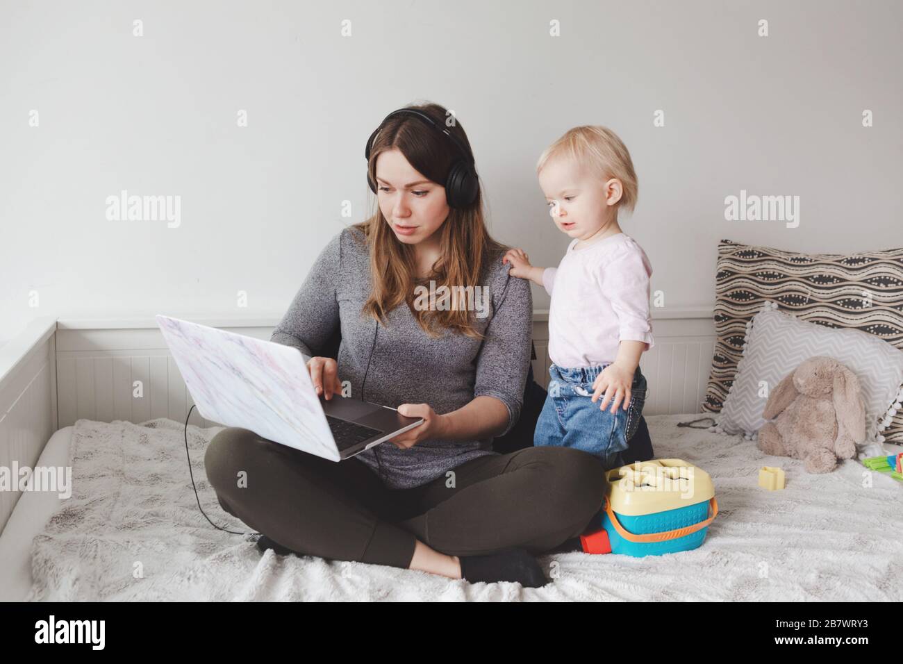 Jeune fille caucasienne blogger avec bébé travaillant sur ordinateur  portable de la maison. Lieu de travail d'une femme étudiante en freelance  avec un enfant tout-petit. Séjournez chez vous à la mère unique