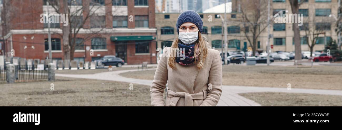 Femme caucasienne dans le masque chirurgical marchant en plein air à Toronto. Masque protecteur contre la pneumonie chinoise COVID-19 épidémie de virus maladie Banque D'Images