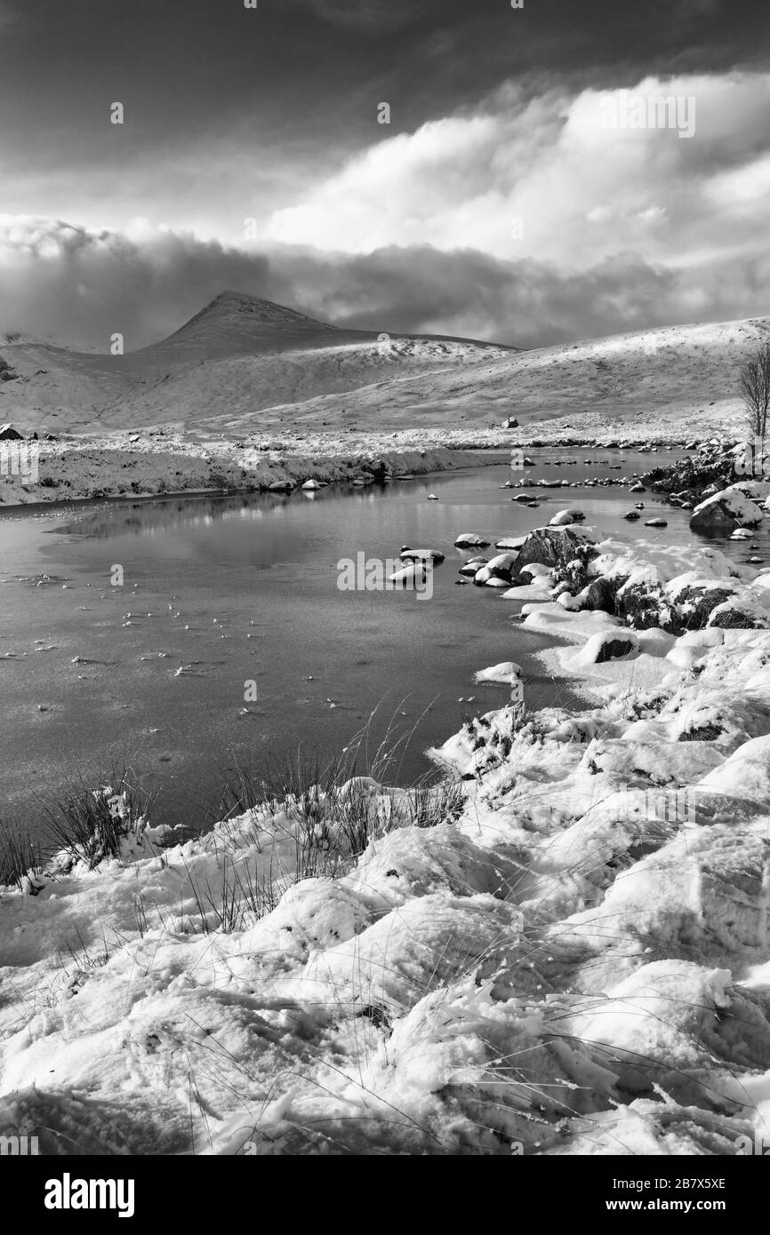 Après-midi d'hiver froid avec loch partiellement gelé et neige au Loch Ba, Rannoch Moor, Argyll et Bute, Ecosse en janvier - noir et blanc monochrome Banque D'Images
