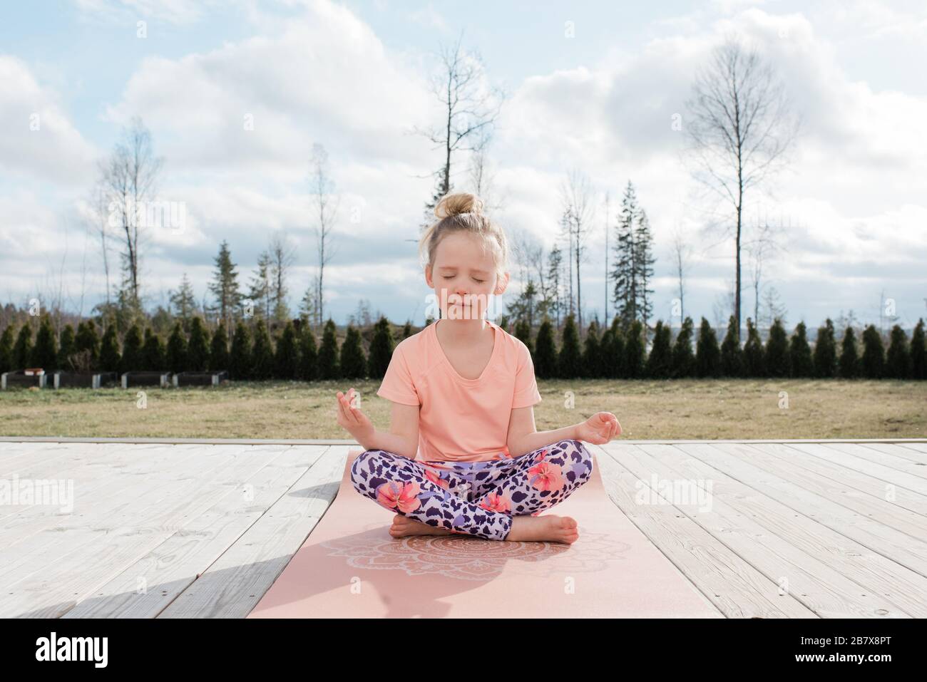 jeune fille méditant faisant du yoga dans son arrière cour à la maison Banque D'Images
