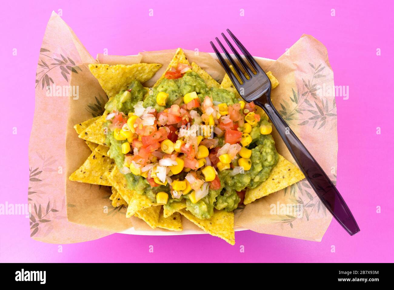 Vue de dessus des nachos mexicains avec fromage et guacamole mélangés avec des légumes Banque D'Images