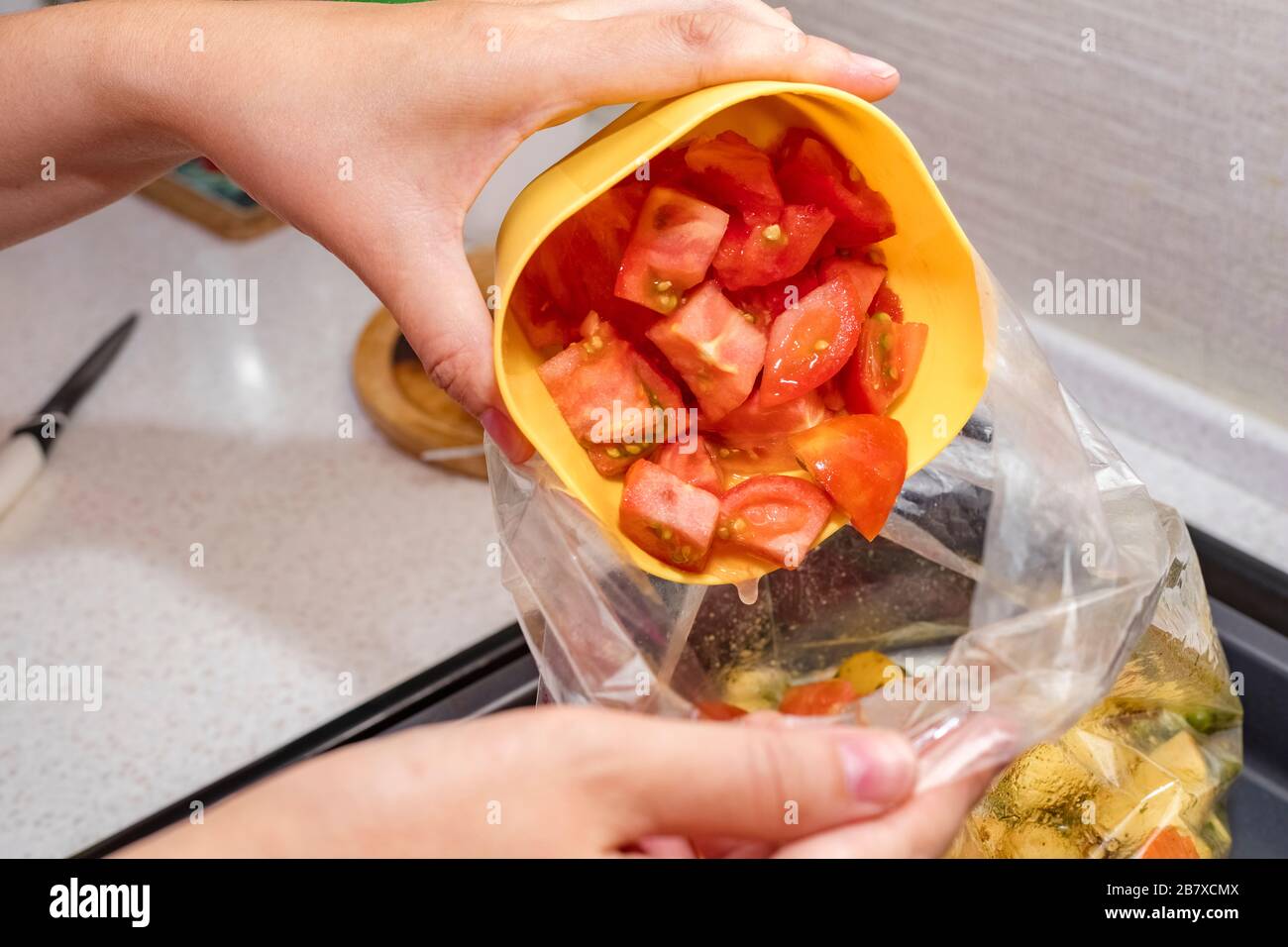 Mains féminines verser les tomates fraîchement hachées dans un sac de légumes. Cuisson. Espace de copie Banque D'Images